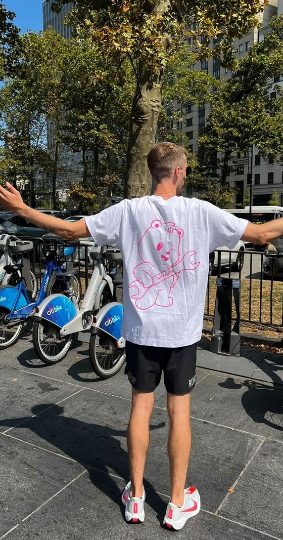 Someone in New York with arms spread, the Art Engine bear across their tee shirt